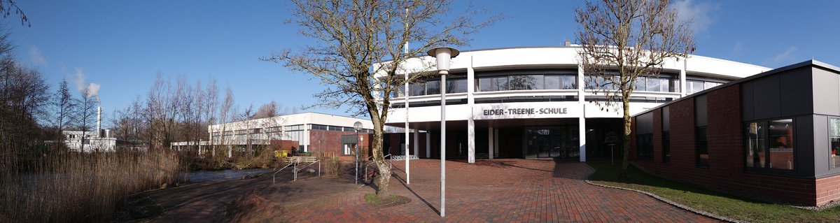 Eider Treene Schule Friedrichstadt von vorne mit einem Pfad der zur Schule führt. Am Pfad entlang sind Bäume.